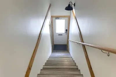 a stairway leading up to a white door with a light at Raven Lady #202- Ucluelet, Sleeps 4, Pet Friendly in Ucluelet