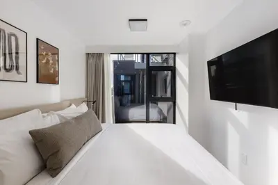 a bedroom with a white bed with a flat screen tv at Keefer House in Vancouver