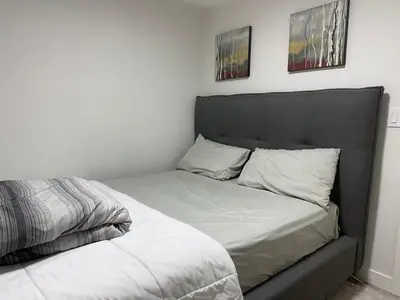 a bed in a bedroom with two pictures on the wall at Maxti Guest Suite, Northwest Calgary in Calgary