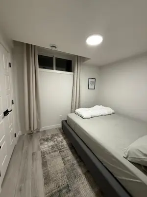 a white bedroom with a bed and a window at Maxti Guest Suite, Northwest Calgary in Calgary