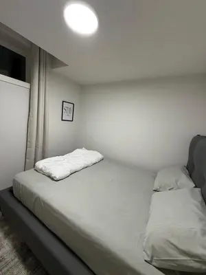 a bed in a room with a white wall at Maxti Guest Suite, Northwest Calgary in Calgary