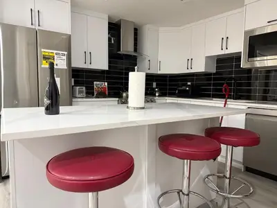 a kitchen with red stools and a counter with a bottle of wine at Maxti Guest Suite, Northwest Calgary in Calgary