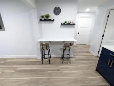 a kitchen with a white table and two stools at Chic 2BR Suite with Kitchen, Laundry, Near Elk Island & West Edmonton Mall in Edmonton
