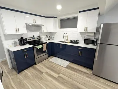 a kitchen with blue cabinets and stainless steel appliances at Chic 2BR Suite with Kitchen, Laundry, Near Elk Island & West Edmonton Mall in Edmonton
