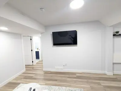 a white room with a television on a wall at Chic 2BR Suite with Kitchen, Laundry, Near Elk Island & West Edmonton Mall in Edmonton
