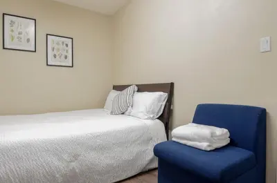 a bedroom with a bed and a blue chair at Convenient Urban Retreat in Vancouver