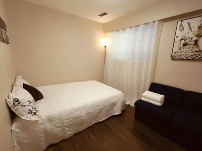 a bedroom with a white bed and a window at Convenient Urban Retreat in Vancouver