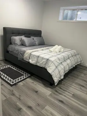 a bedroom with a bed with a blanket and a window at Basement in Keswick Edmonton in Edmonton