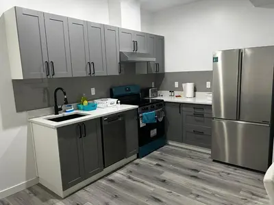a kitchen with gray cabinets and a stainless steel refrigerator at Basement in Keswick Edmonton in Edmonton