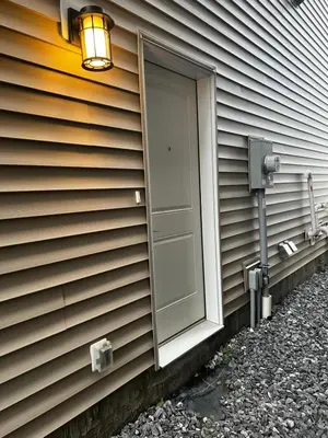 a door on the side of a house with a light at Basement in Keswick Edmonton in Edmonton