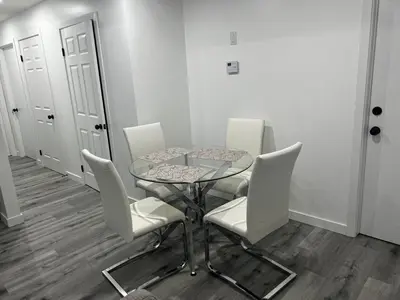 a dining room with a glass table and white chairs at Basement in Keswick Edmonton in Edmonton