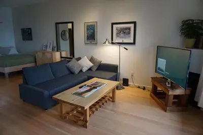a living room with a blue couch and a tv at Tofino Eco Waterfront Condo in Tofino