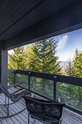 two chairs on a deck with a view of trees at Premium 4-Bedroom Chalet in Whistler