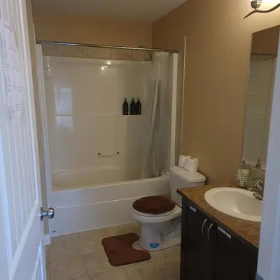a bathroom with a toilet and a tub and a sink at Ogden 3-Bed Home in Calgary
