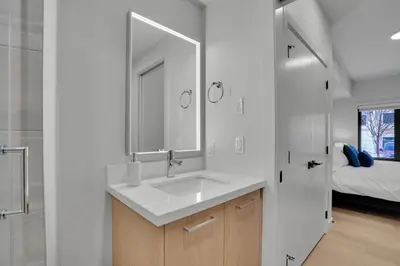 a bathroom with a sink and a mirror and a bed at 3 Bedroom with Heated Outdoor Pool and Hottub! in Canmore