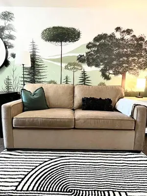 a couch in a living room with trees on the wall at Old Forest Resort Suite Heated Pool Hot Tub Sauna Beach Vancouver Island in Nanoose Bay