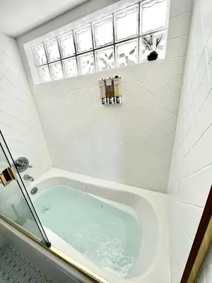 a bath tub in a bathroom with a window at Old Forest Resort Suite Heated Pool Hot Tub Sauna Beach Vancouver Island in Nanoose Bay