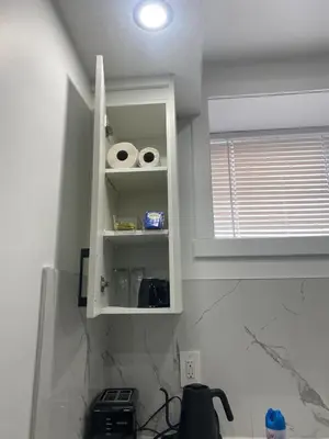a kitchen with white cabinets and a window and a sink at Carrington Cozy Suite, Calgary in Calgary