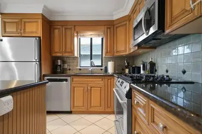 a kitchen with wooden cabinets and white appliances at Lovely 2 Bedroom Kits Home - Walk to the Beach in Vancouver