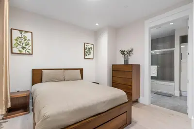 a bedroom with a bed and a dresser and a window at Centrally Located Luxury Home with Views and Cinema in Vancouver