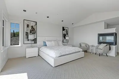 a white bedroom with a bed and a chair at Beautiful 5 bedroom West Vancouver Mansion in West Vancouver