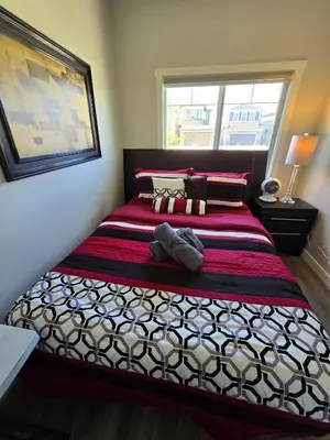 a bedroom with a bed with a red and white blanket at Cornerstone 4-Bed Home in Calgary