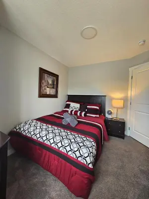 a bedroom with a large bed with a red blanket at Cornerstone 4-Bed Home in Calgary
