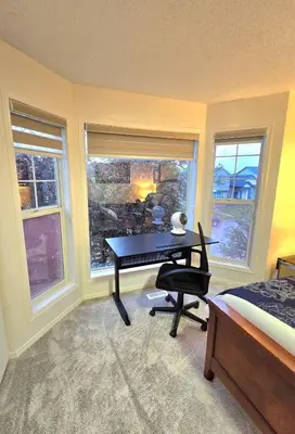 a bedroom with a desk and a bed and windows at Magnificent 3-Bed Home in Calgary