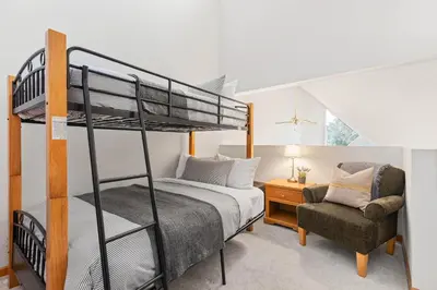 a bedroom with a bunk bed and a chair at 2BR and Loft in Wildwood Lodge, Mountain Views, Close to Ski Hill, Common Hot Tub, Fireplace, Parking in Whistler