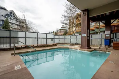 a swimming pool with blue water in a building at 2BR plus Loft and Sofabed in Tyndall Stone Lodge, Epic Village Location, Mountain Views, Pool and Hot Tub in Whistler
