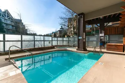 a swimming pool with blue water on a balcony at 2BR plus Loft and Sofabed in Tyndall Stone Lodge, Epic Village Location, Mountain Views, Pool and Hot Tub in Whistler