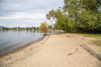 a sandy beach next to a body of water at Chateau Calcaire Carriage House in Kelowna