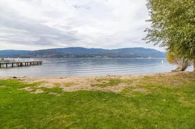 a body of water with a pier and a grass field at Chateau Calcaire Carriage House in Kelowna