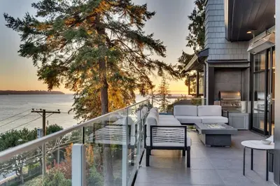 a house with a balcony with a view of the water at The Sunset Lane Waterfront Home in West Vancouver