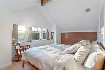 a bedroom with a large white bed with a wooden headboard at Beautiful, Newly Renovated Creek Home in Vancouver