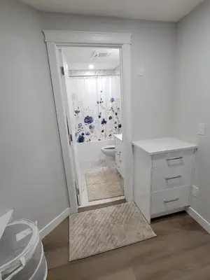 a white bathroom with a shower and a toilet at Cozy and Modern Suite - Your Home Away from Home! in Calgary