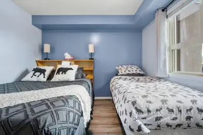 a blue room with two beds and a window at The Beach House Pool Access 5 Min Walk to Lake Sleeps 8 in Invermere