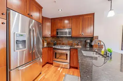 a kitchen with wooden cabinets and stainless steel appliances at Stunning 2bd hot tub walking distance to downtown in Canmore