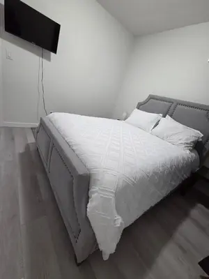 a bed with white sheets and pillows in a bedroom at Elegant & Cozy 2 Bdrm Basement suite near WEM in Edmonton