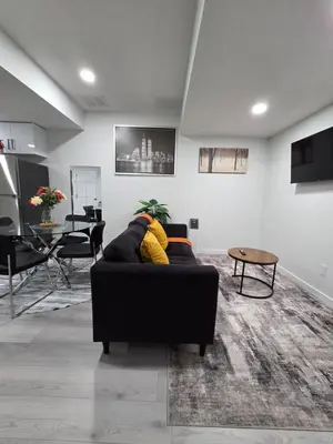 a living room with a black couch and a table at Elegant & Cozy 2 Bdrm Basement suite near WEM in Edmonton