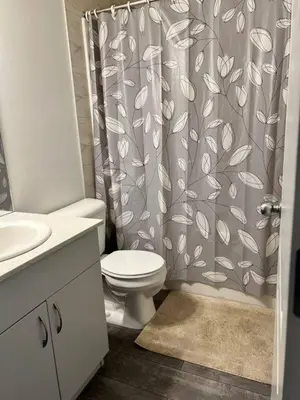 a bathroom with a toilet and a shower curtain at Bedroom in Southwest C in Edmonton