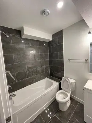 a bathroom with a white tub and a toilet and a sink at Bedroom in Southwest C in Edmonton