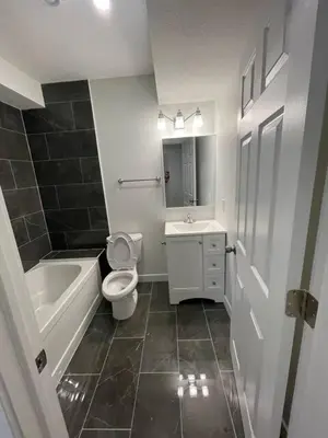 a bathroom with a toilet and a tub and a sink at Bedroom in Southwest D in Edmonton