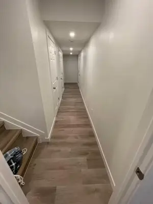 a hallway with white walls and a wooden floor at Bedroom in Southwest D in Edmonton