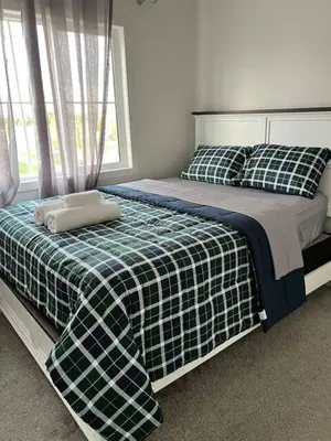 a bedroom with a bed with a plaid blanket and a window at Bedroom with private bathroom in Southwest in Edmonton