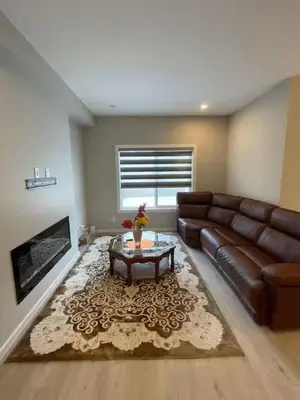 a living room with a leather couch and a coffee table at Brand New Bedroom in Keswick B in Edmonton