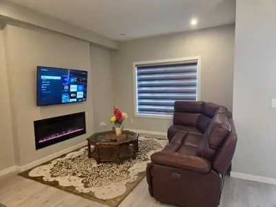 a living room with a chair and a television at Brand New Bedroom in Keswick B in Edmonton
