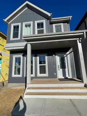 a gray house with a front porch and a person standing in front at Bedroom in Upland A in Edmonton