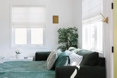 a living room with a green couch and two windows at Brass Apple Cottage in Campbell River