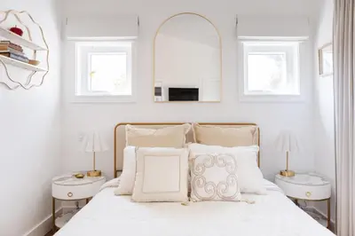 a white bedroom with a bed with two night stands at Brass Apple Cottage in Campbell River